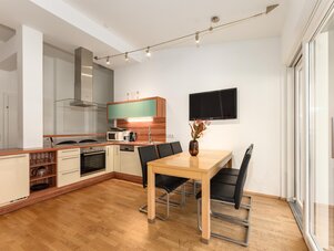 Modern open kitchen with dining table and TV.