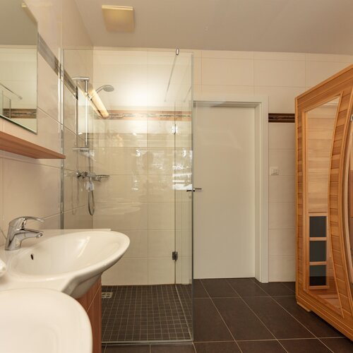 Bright bathroom with glass shower and wooden sauna