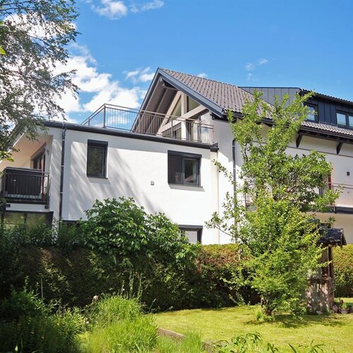 Weißes Mehrfamilienhaus mit Balkonen und Garten