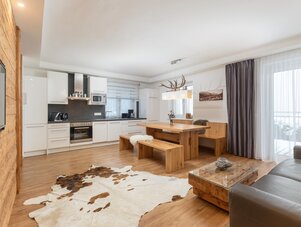 Offene Küche und Essbereich mit Holzmöbeln und Hirschgeweih-Kronleuchter