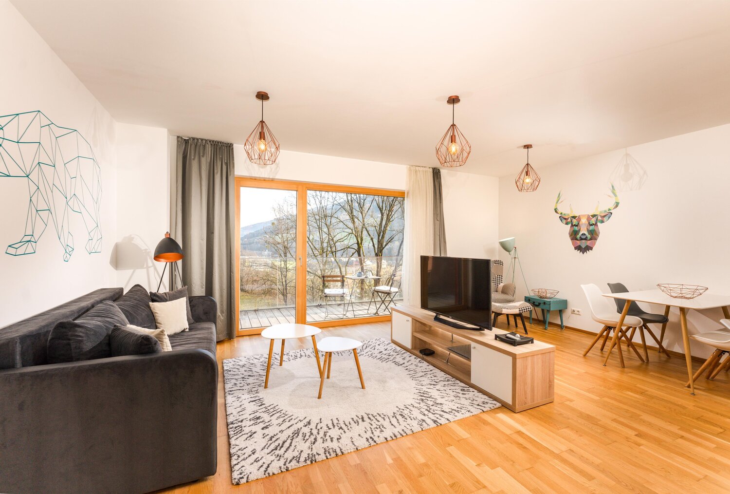 Modernes Wohnzimmer mit grauer Couch, Glastüren und geometrischer Wandkunst