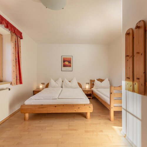 Helles Zimmer mit Doppelbett und Einzelbett aus Holz