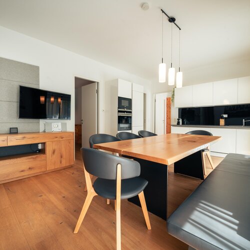 Offener Wohnbereich mit Holztisch und moderner Küche | © TIEBER