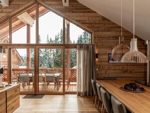 Holz-Chalet Innenraum mit großen Glasfronten und Esstisch