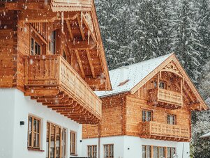 Schneebedecktes alpines Holz-Chalet mit Balkonen und Kiefern