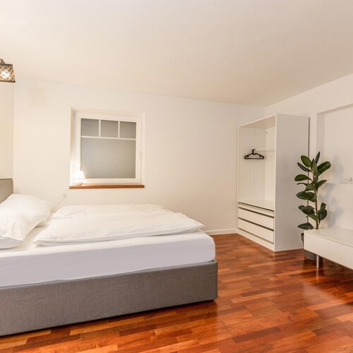 Modernes Schlafzimmer mit Bett, Kleiderschrank und TV-Anlage