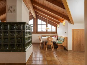 Gemütlicher rustikaler Essbereich mit Holzbalken und Kachelofen