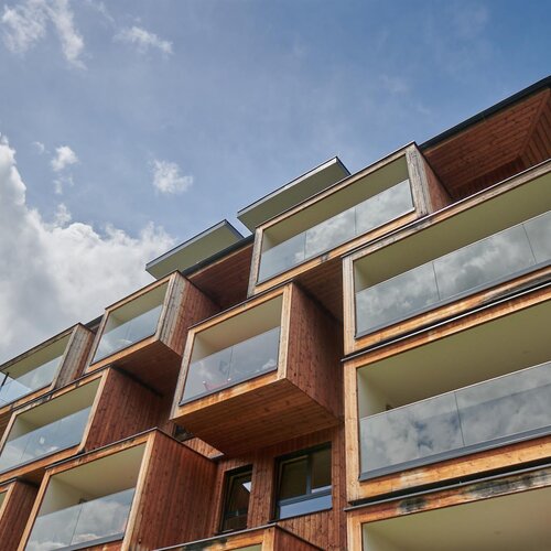 Aufnahme von unten: mehrstöckiges Holzgebäude mit Glasbalkonen