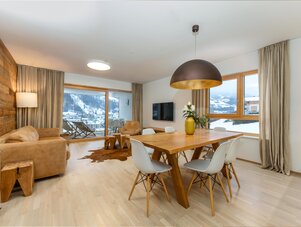 Wohnzimmer und Essbereich mit Holzwand und Schnee draußen.