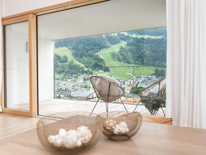 Wohnzimmer mit Schiebetüren zum Balkon mit Blick auf Tal und Dorf