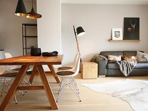 Helles modernes Wohnzimmer mit Esstisch aus Holz und grauem Sofa