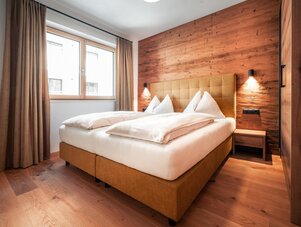 Hotelzimmer mit großem Fenster, braunen Vorhängen und Holzwand