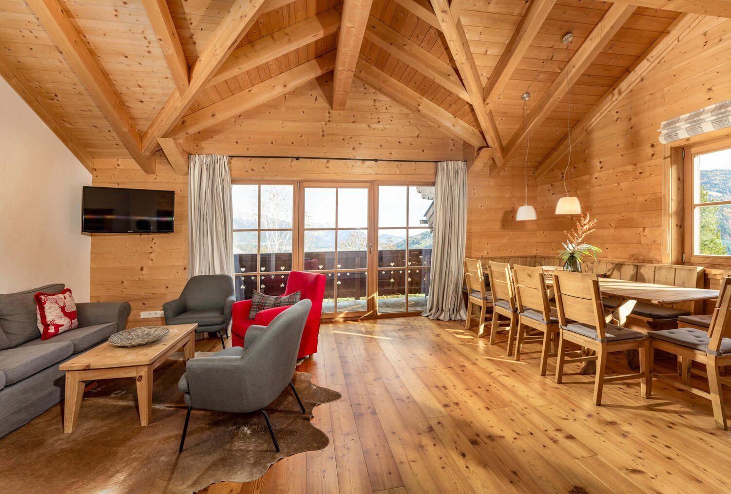 Rustic wooden living room with dining area and mountain view
