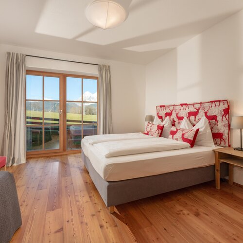 Bright hotel bedroom with large bed and red deer headboard