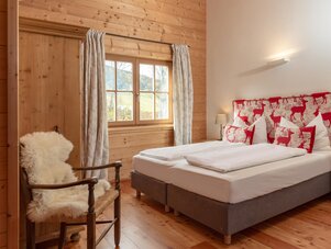 Cozy wood-paneled bedroom with deer-patterned headboard and white bedding