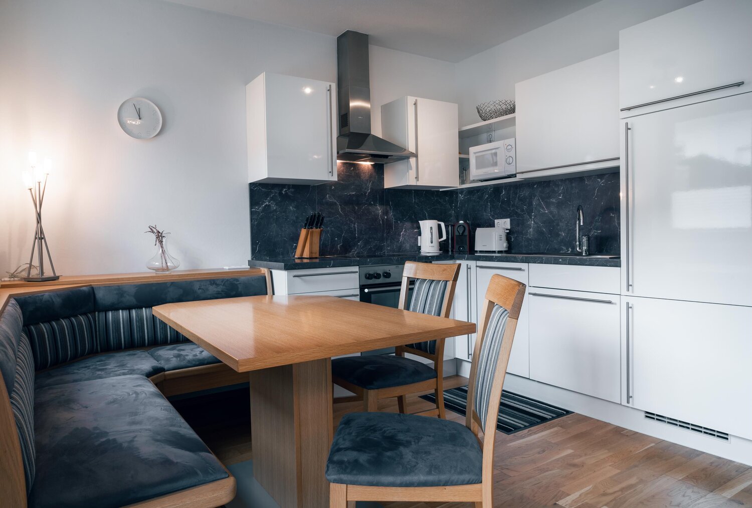 Modern kitchen with white cabinets, dark marble backsplash, and dining table