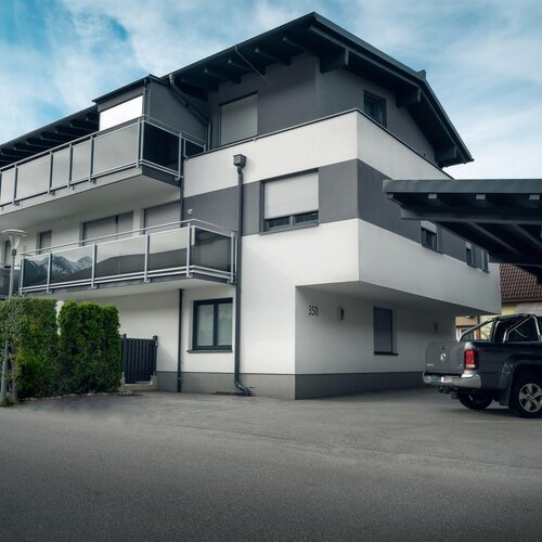 Three-story apartment building with balconies and a carport