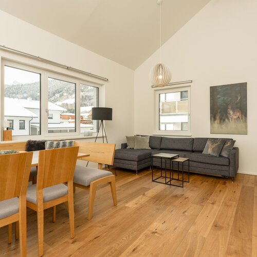 Bright open-plan living and dining room with wooden furniture and mountain views