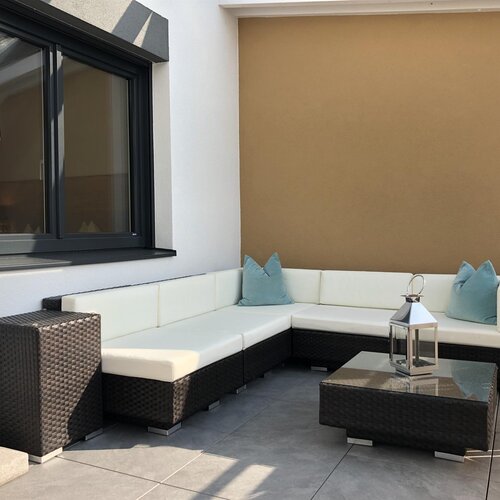 Outdoor wicker sectional sofa with white cushions and blue pillows