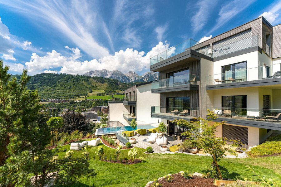 Modern residential building with glass balconies and landscaped garden.